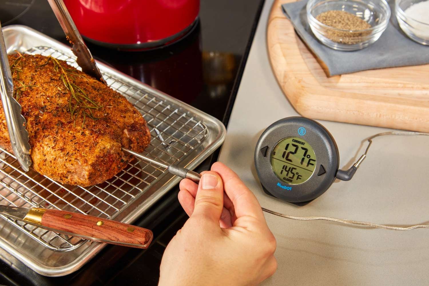 Digital meat thermometer next to grilled steak on wooden board