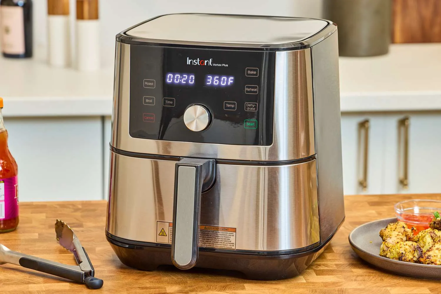 Two air fryer models compared on wooden table with budget notes